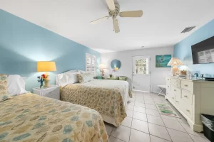 English Garden Bedroom blue and white suite with two beds, a door for the outside, and a ceiling fan - Windemere Inn Florida bed and breakfast