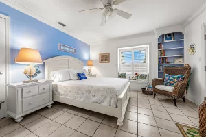 South Beach Bedroom blue and white suite with window, ceiling fan, bookcase, and wicker chairs - Windemere Inn Florida bed and breakfast