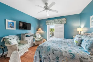 Summer Garden Bedroom blue and white suite with ceiling fan, wicker chairs, and a balcony - Windemere Inn Florida bed and breakfast