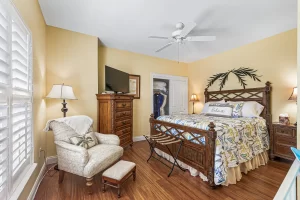 Windsong Bedroom with large closet, queen bed, ceiling fan, and cloth chair - Windemere Inn Florida bed and breakfast