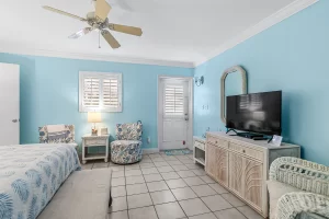 Wavecrest Bedroom blue and white suite with a ceiling fan, sitting area, and a door to the Koi pond - Windemere Inn Florida bed and breakfast