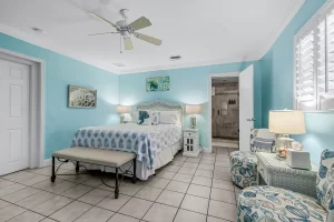 Wavecrest Bedroom blue and white suite with a ceiling fan, queen bed, and sitting area - Windemere Inn Florida bed and breakfast