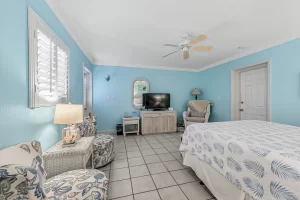 Wavecrest Bedroom blue and white suite with a sitting area, wicker rocking chair, and ceiling fan - Windemere Inn Florida bed and breakfast