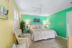 Windsong Bedroom green and yellow suite with a wicker rocking chair and a ceiling fan - Windemere Inn Florida bed and breakfast