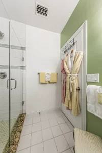 Forever Spring Bathroom green and white bathroom with robes and a walk-in tiled shower - Windemere Inn Florida bed and breakfast