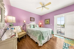 Forever Spring Bedroom pink and white suite with a queen bed, ceiling fan, chair, and balcony door - Windemere Inn Florida bed and breakfast