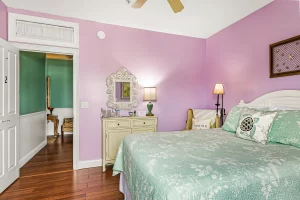 Forever Spring Bedroom pink and white suite with a queen bed, ceiling fan, and chair - Windemere Inn Florida bed and breakfast