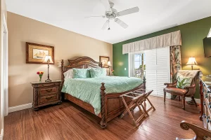 Melbourne Bedroom green and tan suite with a ceiling fan and balcony - Windemere Inn Florida bed and breakfast