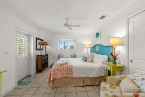 North Beach Bedroom orange and white suite with a cloth chair, king size bed, ceiling fan, and window - Windemere Inn Florida bed and breakfast