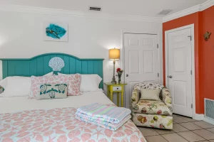 North Beach Bedroom orange and white suite with a king bed and cloth chair for sitting - Windemere Inn Florida bed and breakfast