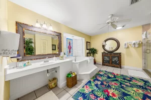 Seabreeze Bathroom yellow and white suite with a vanity, large jetted bathtub, window, ceiling fan, and tiled walk-in shower - Windemere Inn Florida bed and breakfast