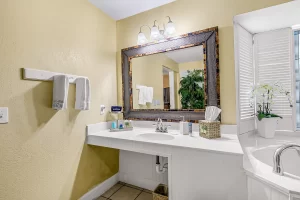 Seabreeze Bathroom yellow and white suite with a wide vanity with a large mirror above, and next to a large jetted bathtub - Windemere Inn Florida bed and breakfast