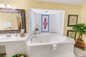 Seabreeze Bathroom yellow and white suite with a large jetted bathtub with a window, and next to the vanity - Windemere Inn Florida bed and breakfast