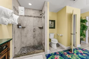 Seabreeze Bathroom yellow and white suite with a large walk-in, stone tiled shower - Windemere Inn Florida bed and breakfast