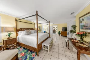 Seabreeze Bedroom yellow and white suite king sized bed, bench, chair with foot rest, and table - Windemere Inn Florida bed and breakfast