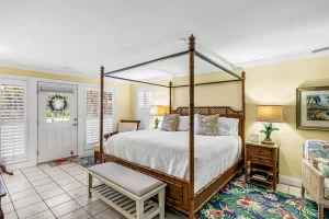 Seabreeze Bedroom yellow and white suite king sized bed with bench and door to the porch - Windemere Inn Florida bed and breakfast