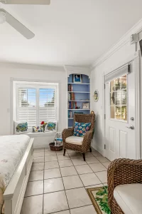 South Beach Bedroom blue and white suite with a ceiling fan, wicker chairs, window, bookcase, and porch door - Windemere Inn Florida bed and breakfast